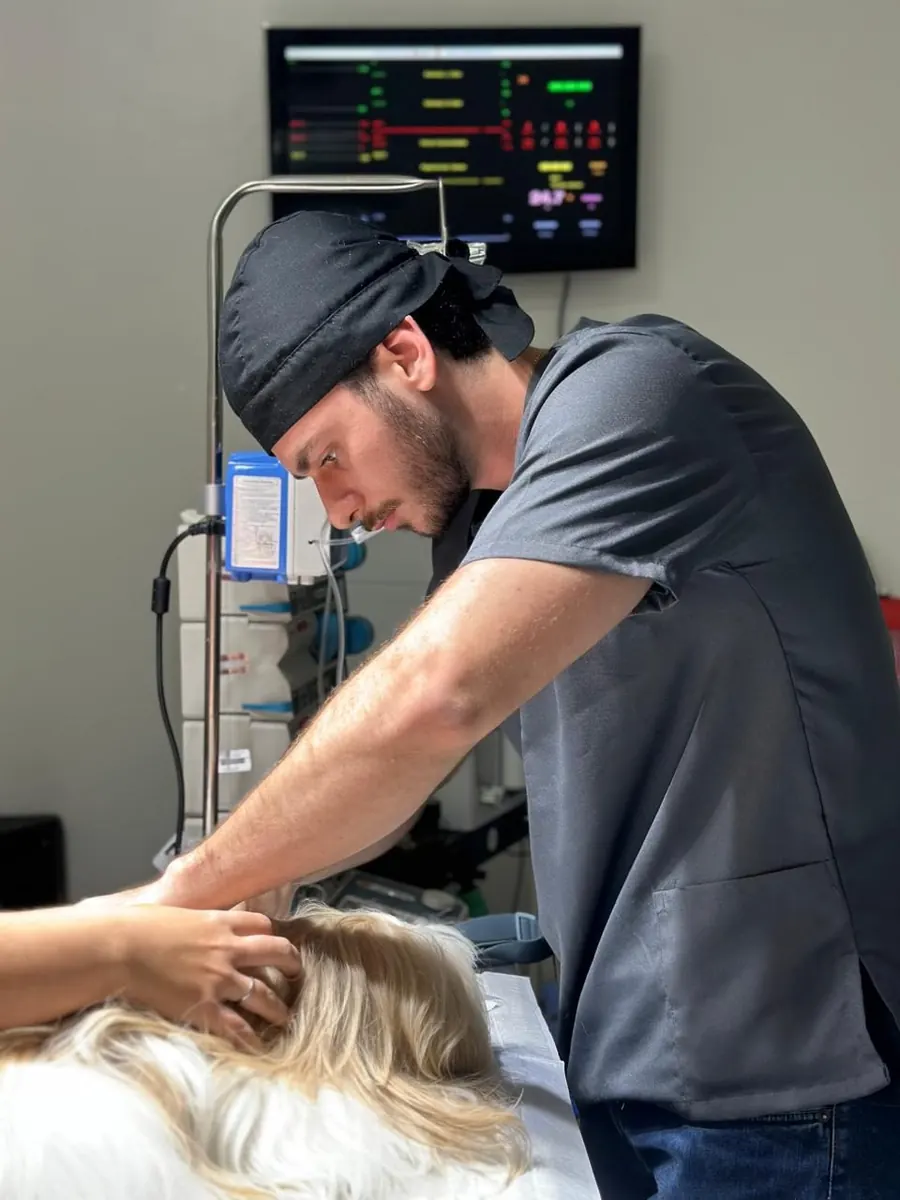Gustavo Lopes acompanhando paciente canino anestesiado, com monitor multiparamétrico ao fundo